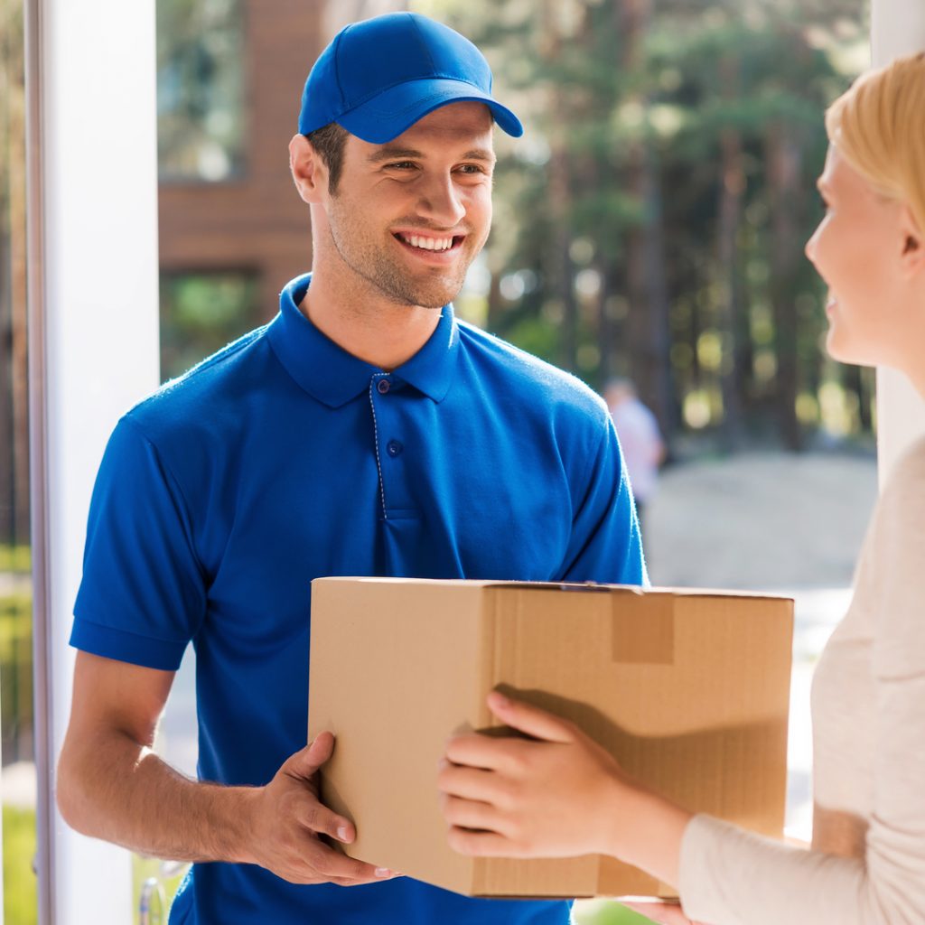 A delivery person drops off a package to a happy customer.