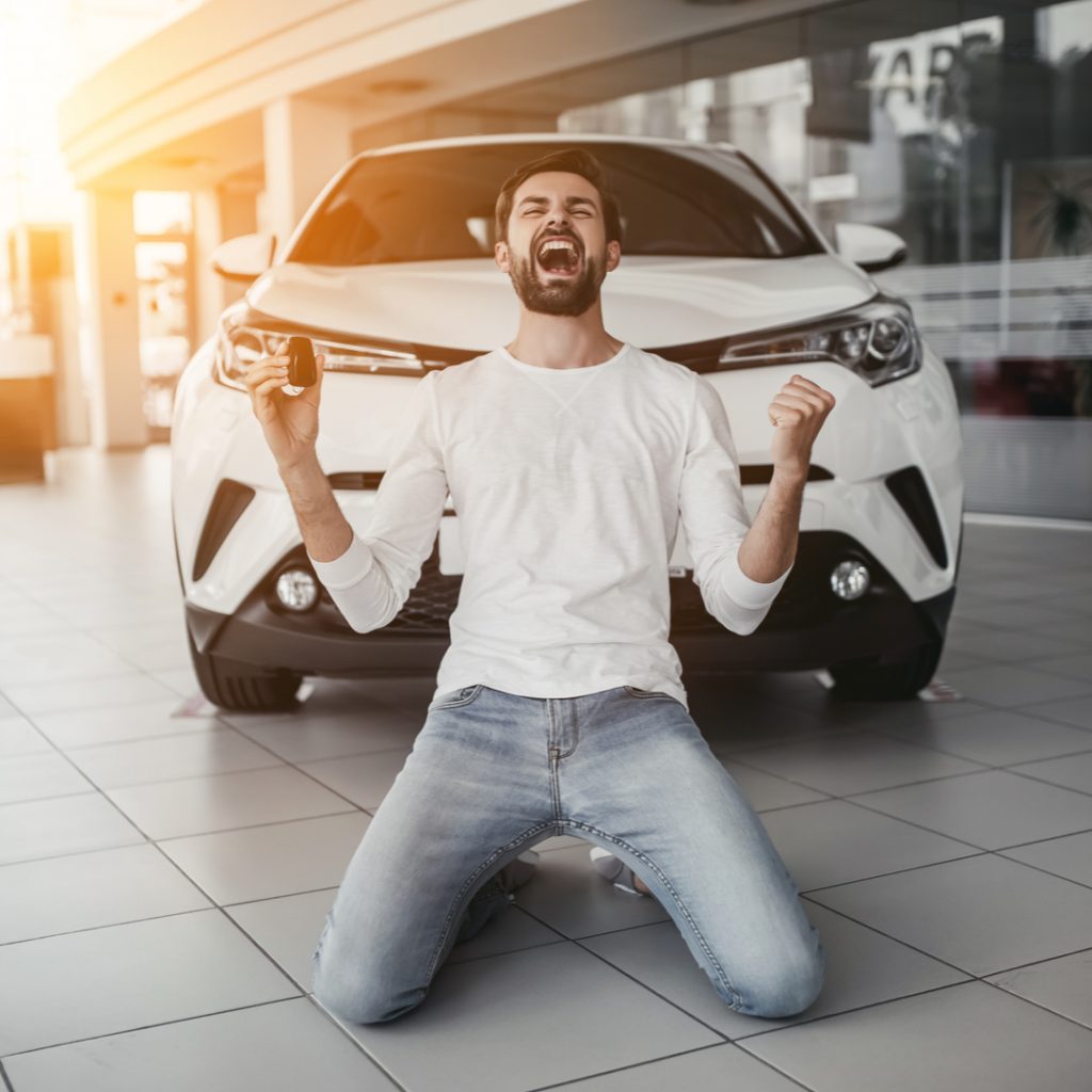 A man is overcome with joy as he is handed the keys to his new car.