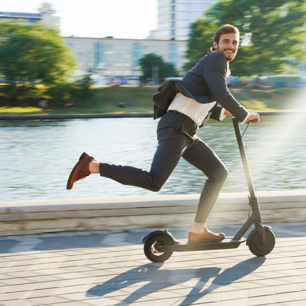 A young businessman happily commutes to work on an electric scooter-an item DealDash has up for auction.