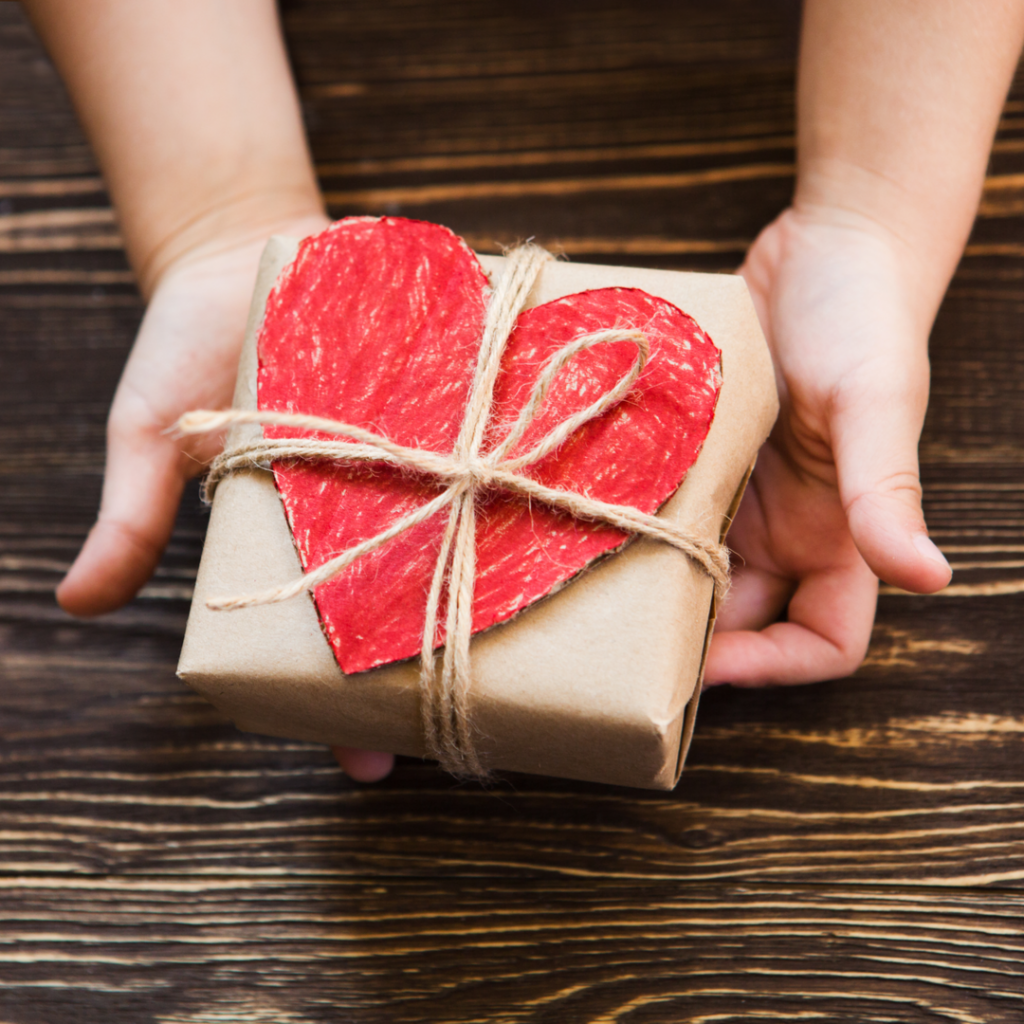 A pair of hands holds a wrapped Christmas gift in a display of generosity.