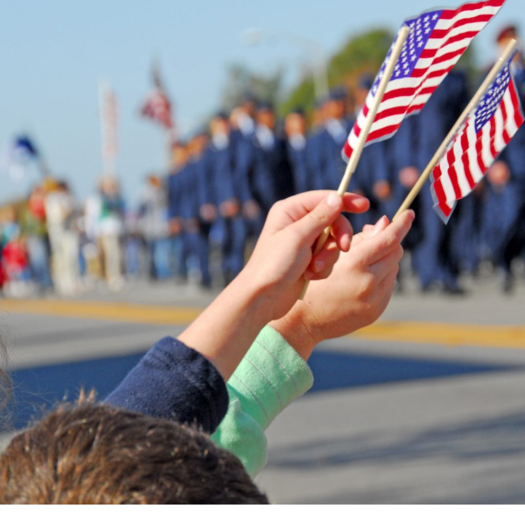 A child holds a small American flag as he cheers a Veterans Day parade.