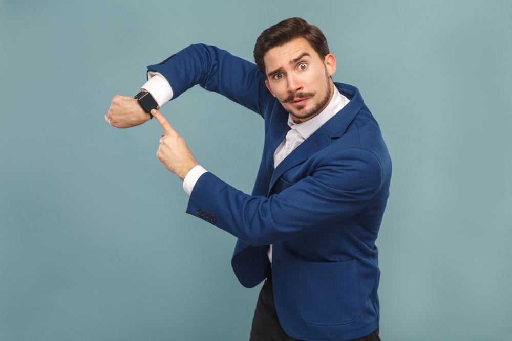 A man points to his watch to tell you to go bid on DealDash!