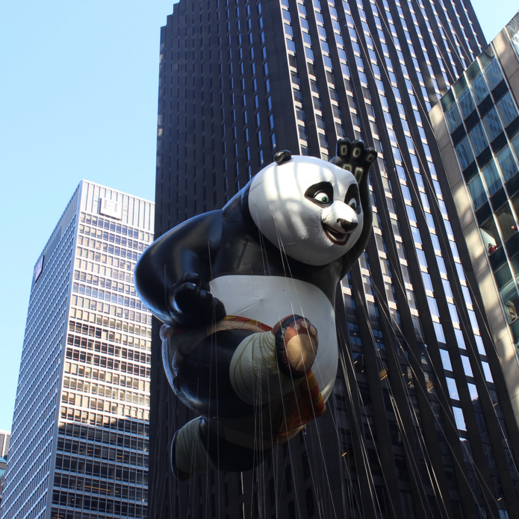 A large balloon panda floats over the crowd at a holiday parade in New York City.