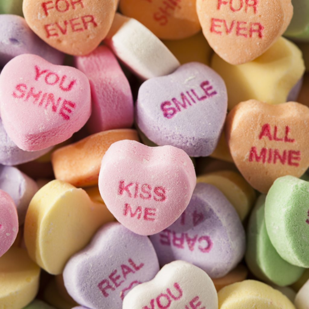 A pile of candy hearts wait to be given out and eaten.