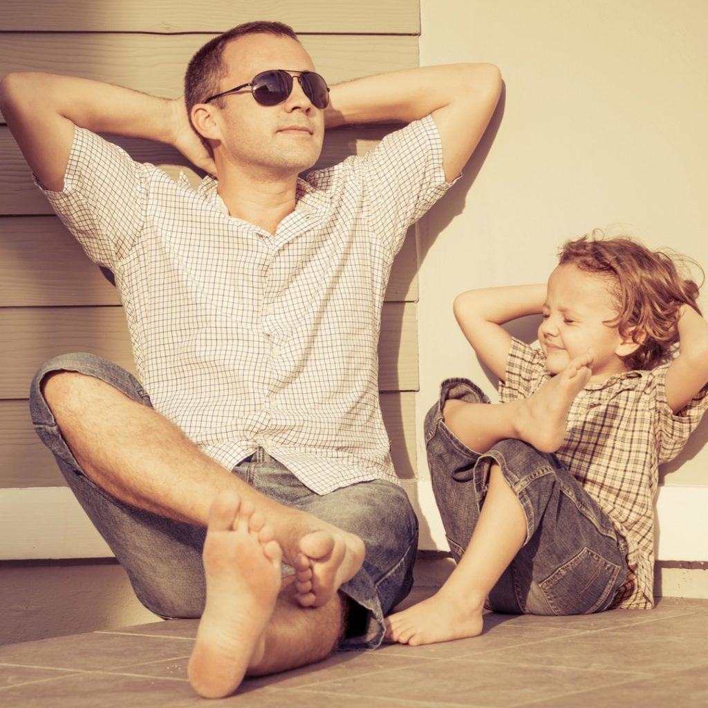 A father and son both relax and enjoy a moment in the sunshine.