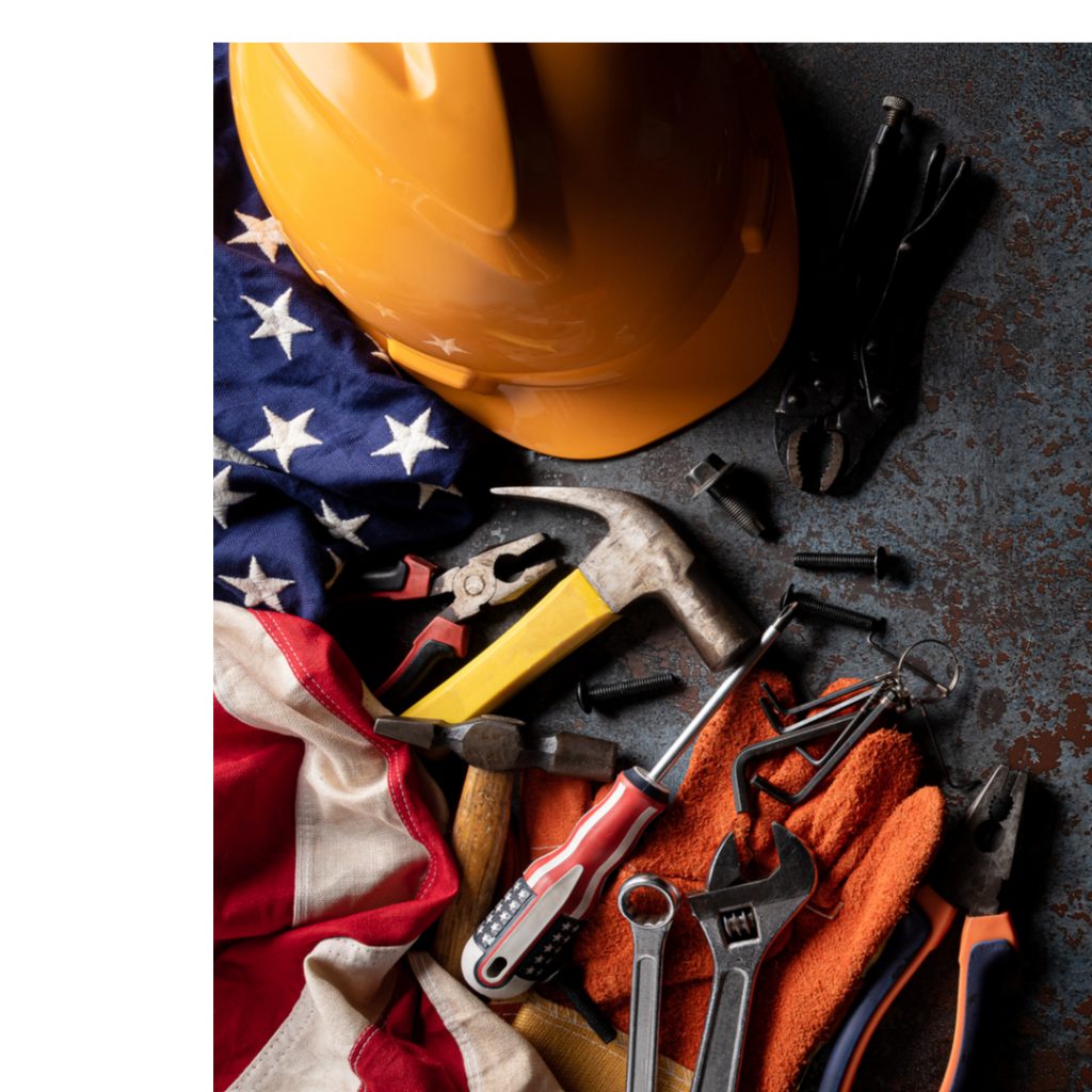 Tools and a construction helmet lie next to an American flag.